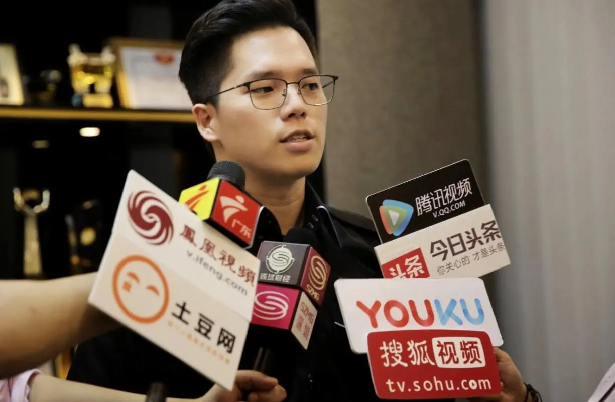 Dr. Jovian Tan answering questions at a press conference, facing microphones from several Chinese media outlets