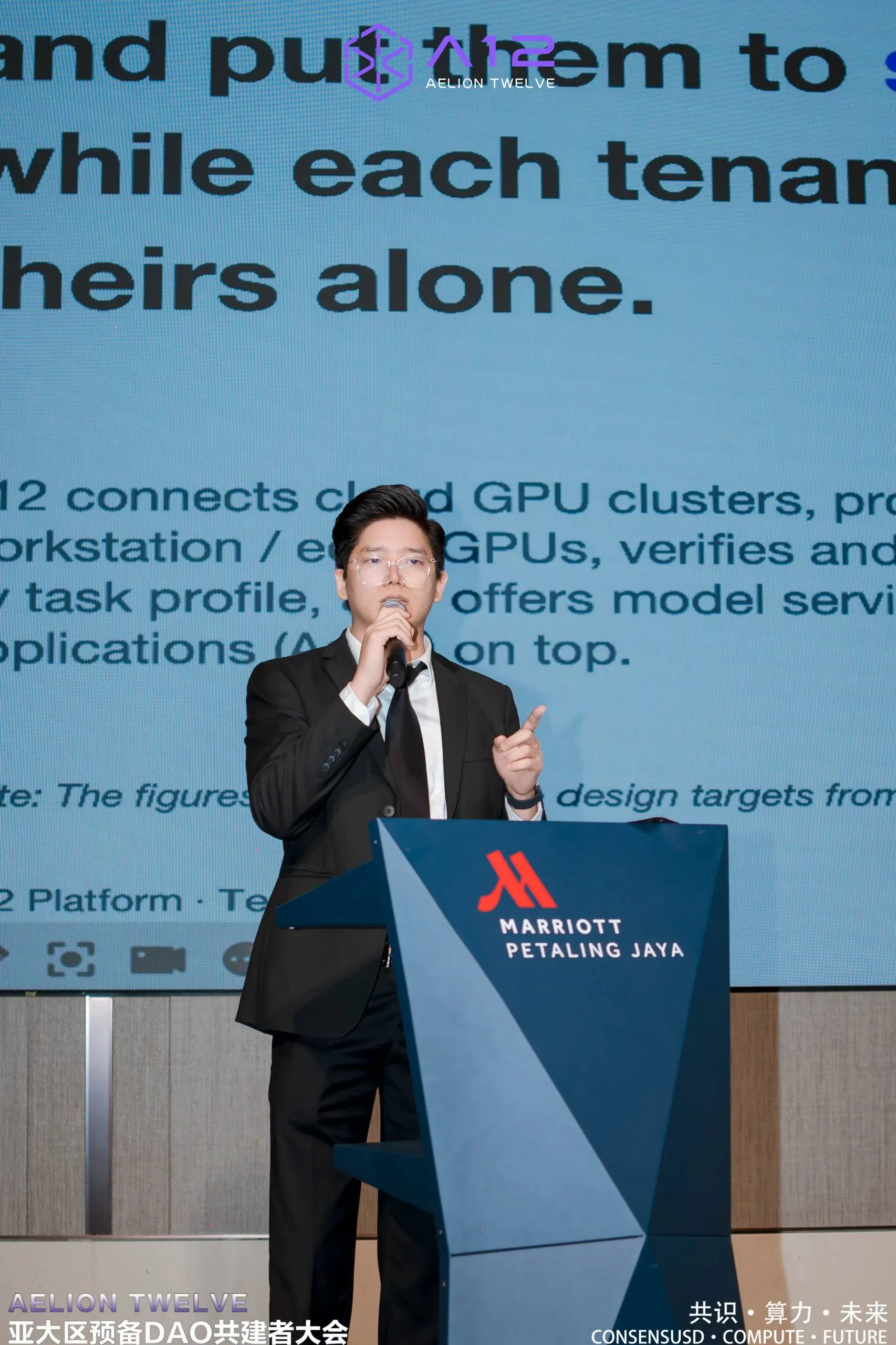 Dr. Jovian Tan speaking at a lectern in front of a presentation slide about GPU clusters
