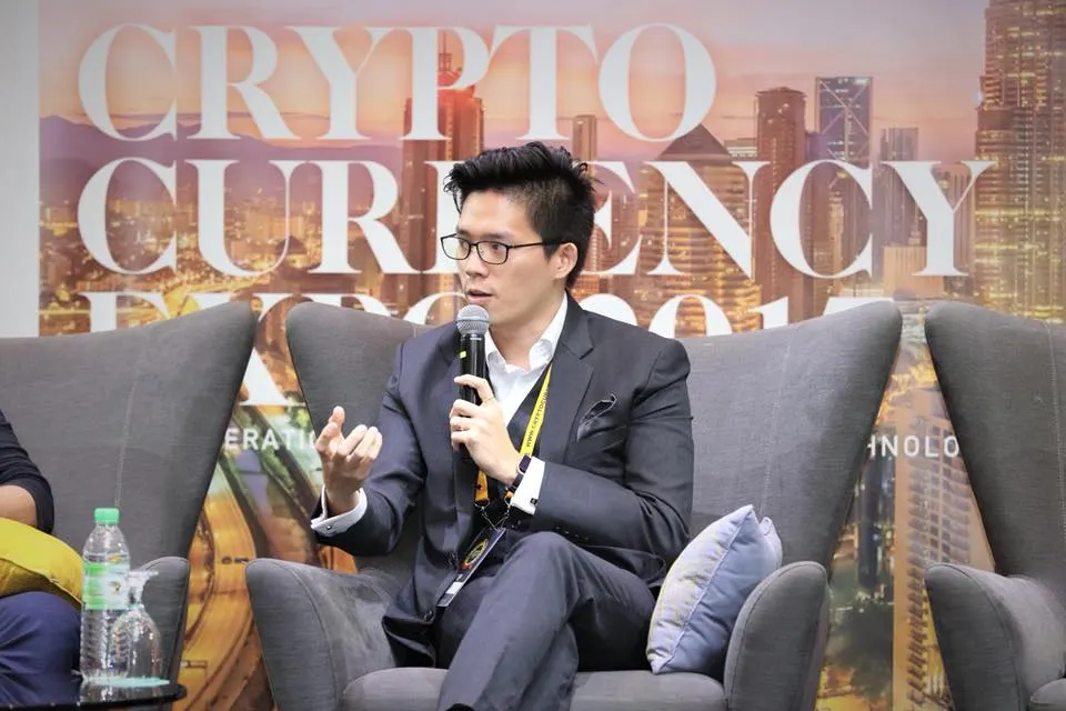 Dr. Jovian Tan speaking on a panel, seated in an armchair with a microphone