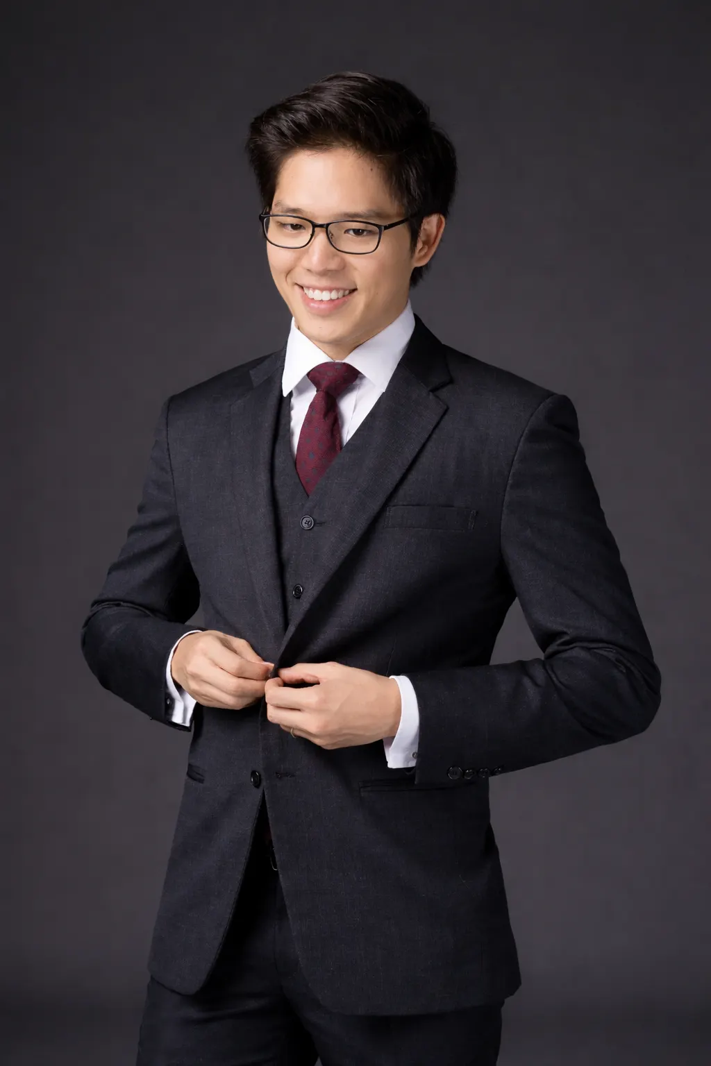 Dr. Jovian Joris Tan Chern Chian smiling and buttoning a dark three-piece suit